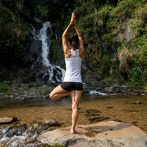 Woman doing yoga near waterfall