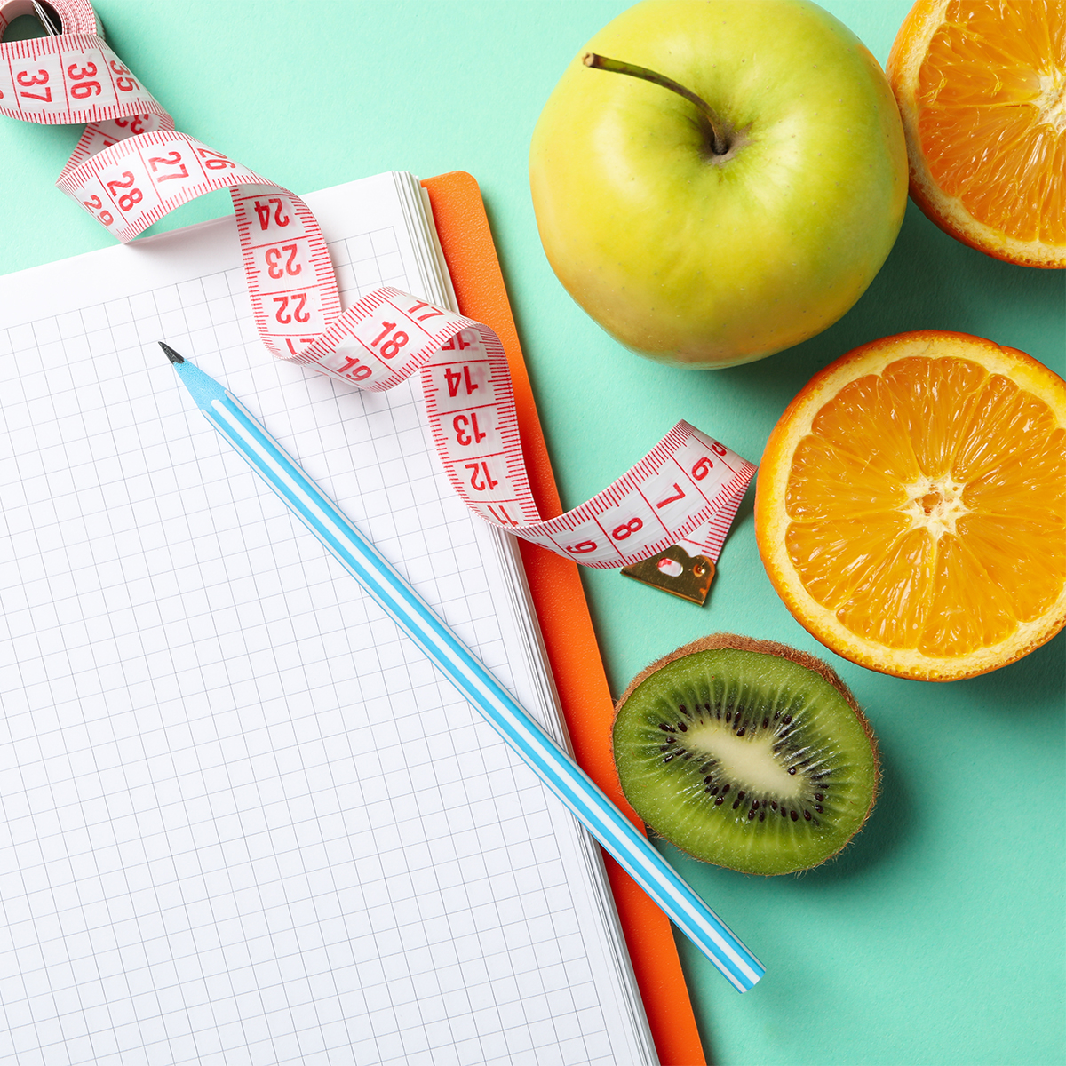 Notebook, measuring tape, pen and vegetarian food on mint backgr